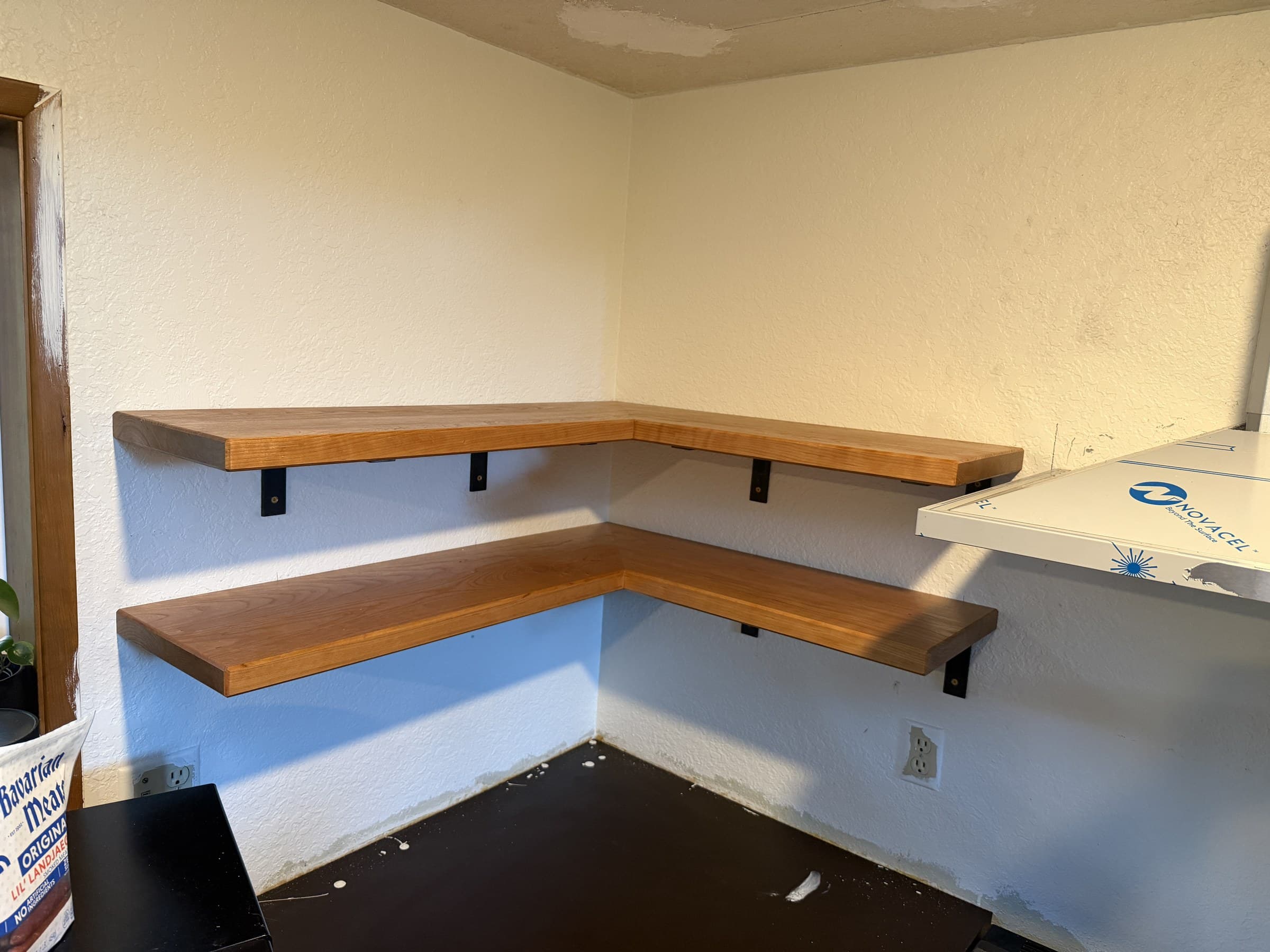 Finished cherry shelves installed around a kitchen corner on black brackets