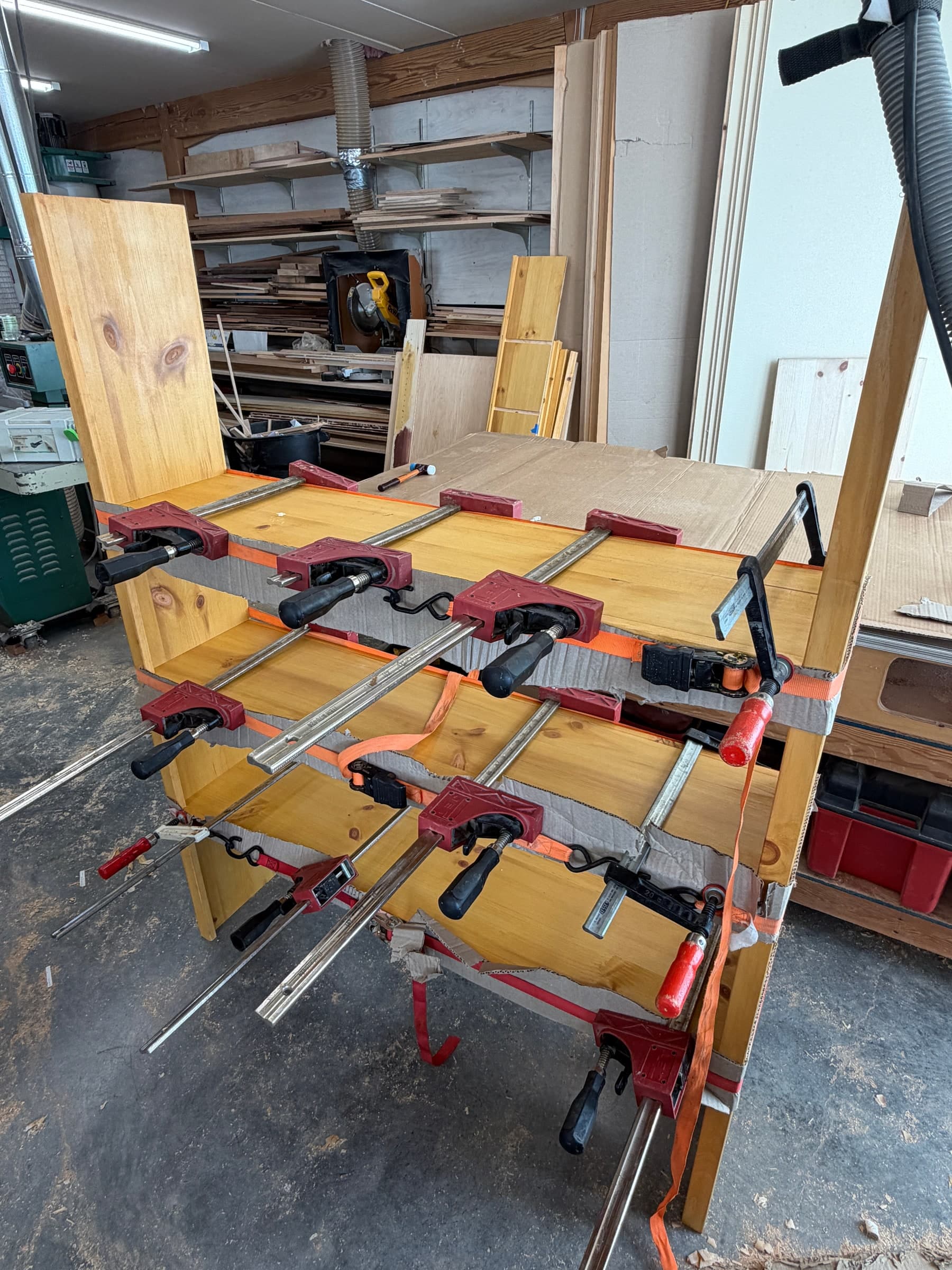 Three shelves fitted into dadoed vertical sides and held with ratchet straps and bar clamps in the shop