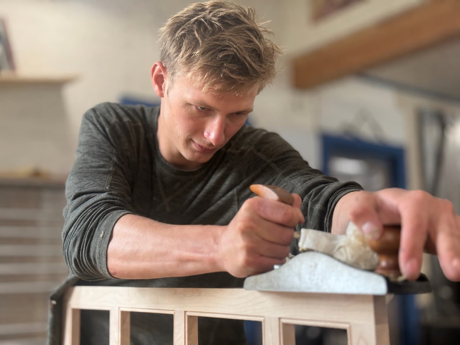 Aidan Gilbert hand planing a cabinet part at the shop bench